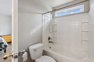 Bathroom with shower / bathing tub combination, wood-type flooring, and toilet