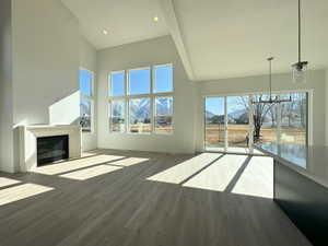 Unfurnished living room featuring high vaulted ceiling, a mountain view, and hardwood / wood-style floors