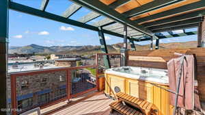 Wooden terrace with a hot tub, a mountain view, and a pergola