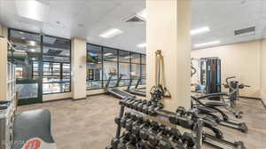 Exercise room with a drop ceiling and light carpet