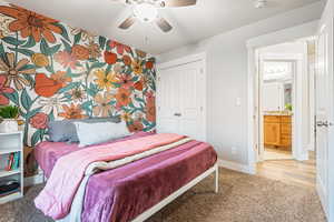 Carpeted bedroom featuring ceiling fan and a closet