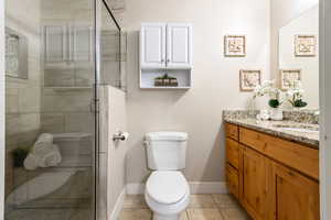 Bathroom with vanity, walk in shower, tile patterned floors, and toilet