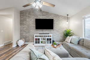 Living room with ceiling fan, lofted ceiling, and dark hardwood / wood-style flooring