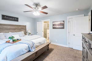 Carpeted bedroom with ceiling fan and ensuite bath