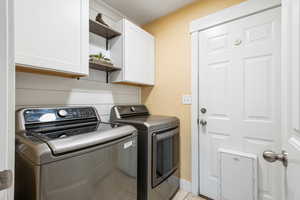 Laundry area featuring independent washer and dryer, cabinets, and light tile patterned flooring