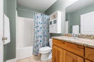 Full bathroom with shower / tub combo, vanity, tile patterned flooring, and toilet