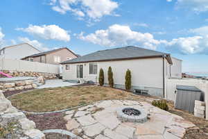 Back of house with a patio, a yard, and a fire pit