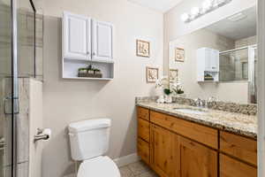 Bathroom with tile patterned flooring, vanity, toilet, and an enclosed shower