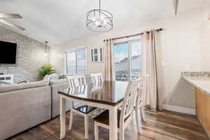 Dining space with dark hardwood / wood-style flooring, vaulted ceiling, and a healthy amount of sunlight