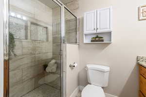 Bathroom with vanity, an enclosed shower, and toilet