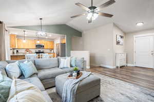 Living room with wood-type flooring, lofted ceiling, sink, and ceiling fan