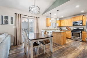 Kitchen with sink, decorative light fixtures, dark hardwood / wood-style flooring, stainless steel appliances, and light stone countertops