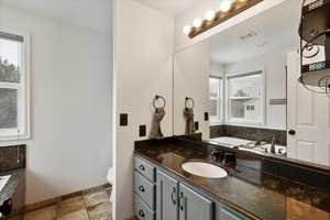 Bathroom with vanity, toilet, and a wealth of natural light