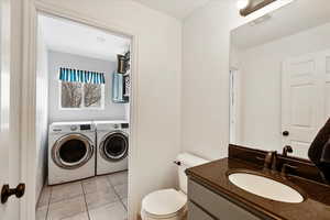 Bathroom featuring independent washer and dryer, vanity, toilet, and tile patterned flooring