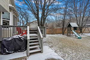 Yard layered in snow featuring a playground