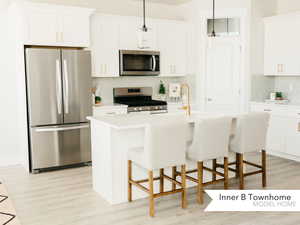 Kitchen with stainless steel appliances, a kitchen island with sink, and white cabinets