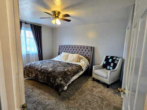 Bedroom with ceiling fan, a textured ceiling, and carpet