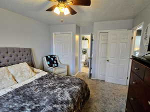 Bedroom featuring light carpet, ceiling fan, a textured ceiling, and ensuite bathroom