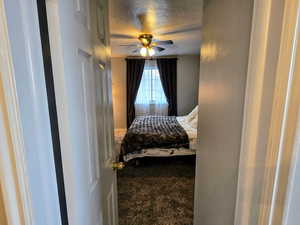 Carpeted bedroom with ceiling fan and a textured ceiling