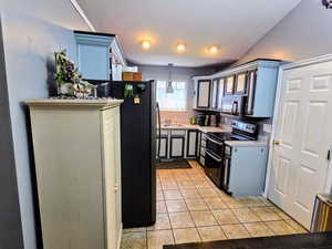 Kitchen featuring stainless steel appliances, sink, hanging light fixtures, and light tile patterned floors