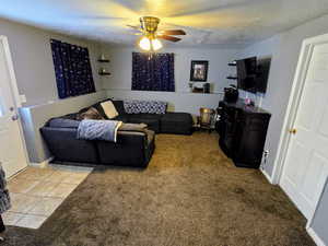 Carpeted living room featuring ceiling fan