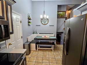 Kitchen featuring hanging light fixtures, light tile patterned floors, stainless steel appliances, and a chandelier