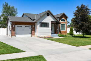 View of front of property with an attached garage, driveway, and a shingled roof