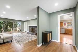 Living room featuring sink, a stone fireplace, and light hardwood / wood-style flooring