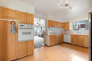 Kitchen featuring plenty of natural light, sink, white appliances, and kitchen peninsula