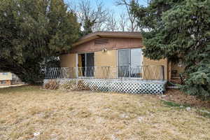 Back of house with a wooden deck and a lawn