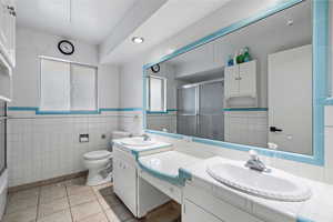 Bathroom with vanity, toilet, tile patterned flooring, and tile walls