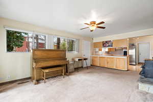 Misc room featuring ceiling fan, light colored carpet, and a wood stove