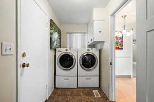 Laundry room featuring cabinets, washing machine and clothes dryer, and a chandelier