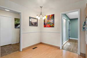 Unfurnished dining area featuring an inviting chandelier and wood-type flooring