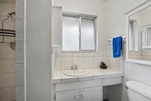 Bathroom featuring vanity, decorative backsplash, and toilet