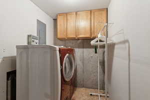 Laundry room with electric panel and cabinets