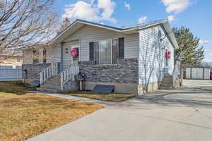 View of front of property featuring a front yard and a storage shed