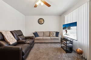 Carpeted living room with ceiling fan