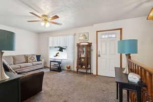 Living room featuring ceiling fan and carpet flooring