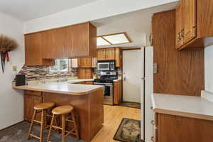 Kitchen with tasteful backsplash, a breakfast bar, appliances with stainless steel finishes, and kitchen peninsula