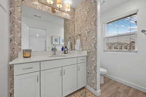 Bathroom featuring hardwood / wood-style flooring, vanity, and toilet