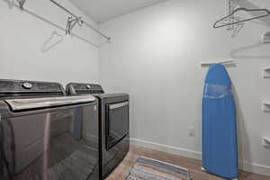 Clothes washing area featuring wood-type flooring and washer and clothes dryer