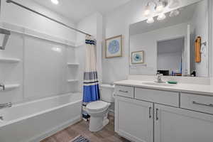 Full bathroom featuring shower / bath combo, hardwood / wood-style floors, vanity, and toilet