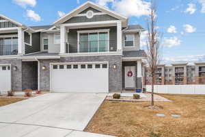 View of front of home featuring a balcony, a garage, and a front yard