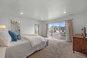 Bedroom with ensuite bathroom, carpet floors, a textured ceiling, and access to outside