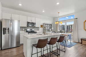 Kitchen with a kitchen island with sink, sink, stainless steel appliances, and white cabinets