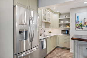 Kitchen featuring sink, light hardwood / wood-style flooring, stainless steel appliances, decorative backsplash, and cream cabinetry