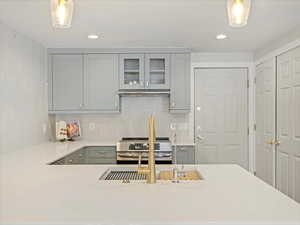 Kitchen with hanging light fixtures, tasteful backsplash, gray cabinetry, and stainless steel electric range