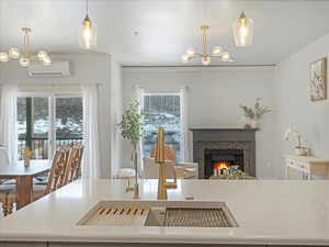 Dining space featuring an AC wall unit, sink, and an inviting chandelier