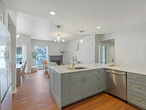 Kitchen featuring wood-type flooring, sink, white fridge, stainless steel dishwasher, and kitchen peninsula